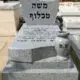 מצבת אבן גרניט לבנה עם כיתוב שחור ומשטח מוגבהה וכד מעוצב מעל המצבה